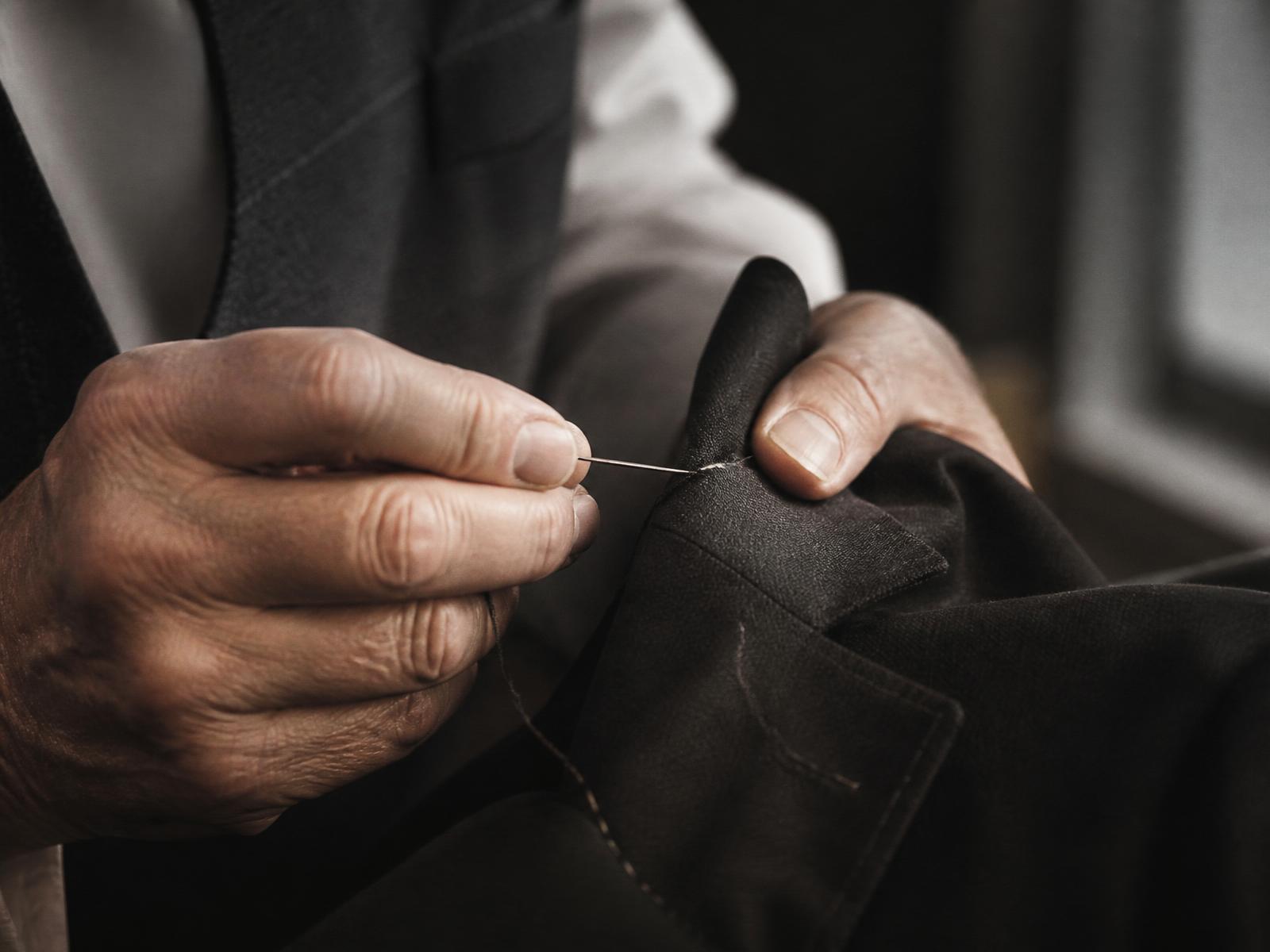 A master tailor hand-stitching a wool lapel in the Santo Velo atelier